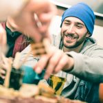 Happy guy with friends eating finger food and drinking beer at pub - Cheerful people having fun at brewery bar restaurant corner - Friendship concept on vintage desaturated filter with focus on face